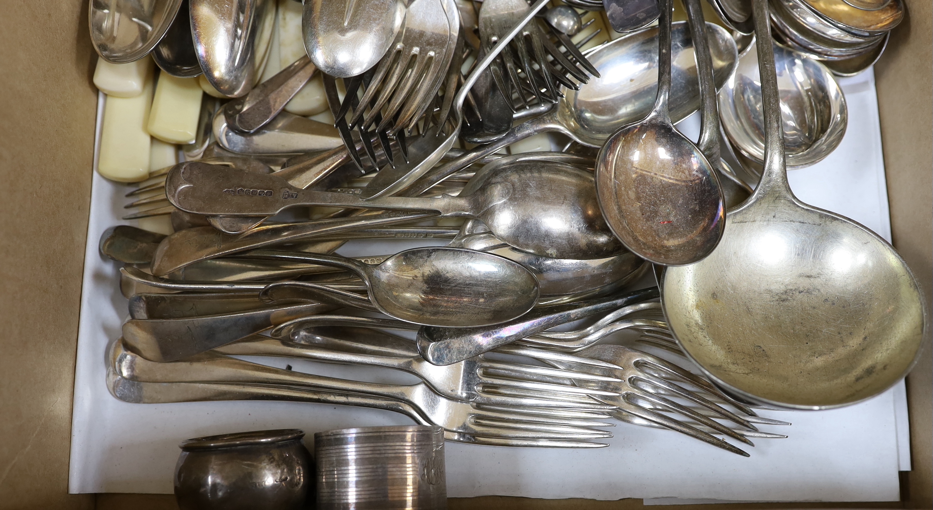 Three silver napkin rings, three silver spoons and a quantity of silver plated cutlery.